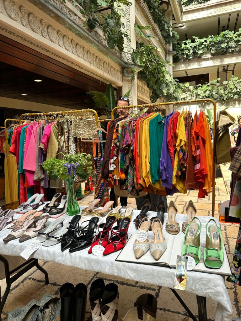 Vibrant vintage clothing and shoes displayed indoors with lush greenery.